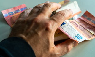 Geldscheine und eine Hand die danach greift