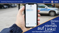 Auf dem Foto hält eine Hand ein Mobiltelefon, auf dem eine betrügerische SMS mit dem Inhalt „Ihr Paket kommt an, verfolgen Sie es hier: [link]“ zu sehen ist. Die Polizei warnt im Bild davor, solche Links anzuklicken.